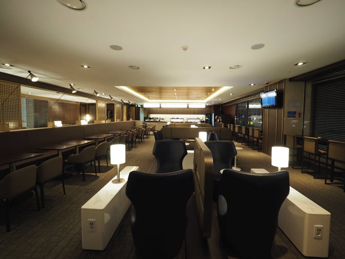 The Sky Hub Lounge at Gimpo International Airport features a spacious seating area with tables, chairs, and individual lamps for travelers.
