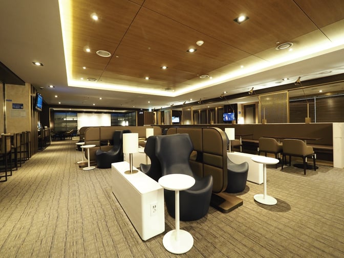 The Sky Hub Lounge at Gimpo International Airport features a spacious seating area with individual tables and semi-private booths.