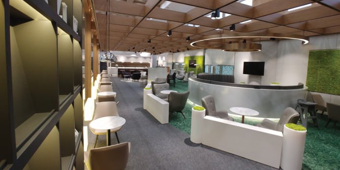 The Sky Hub Lounge at Gimpo International Airport features varied seating arrangements, including tables and chairs, with a central circular partition.