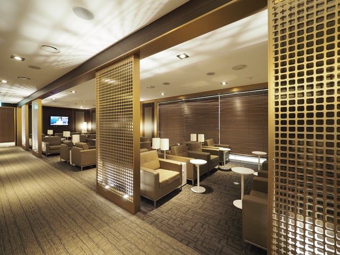 The seating area in MATINA Lounge at Seoul Incheon International Airport features comfortable chairs, small tables, and a television for entertainment.