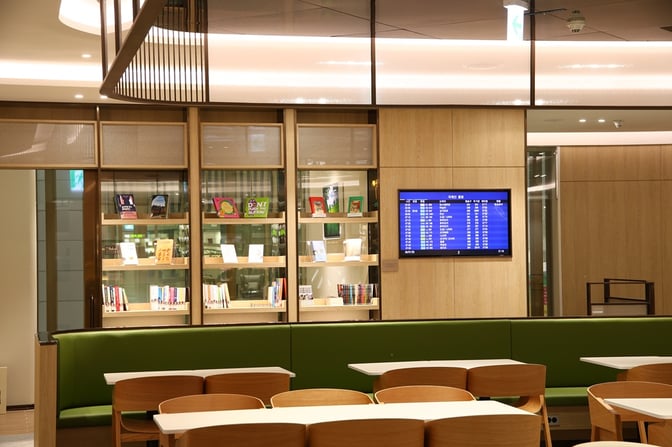 The Sky Hub Lounge East T2 at Seoul Incheon Airport features a seating area with tables, chairs, and a flight information display.