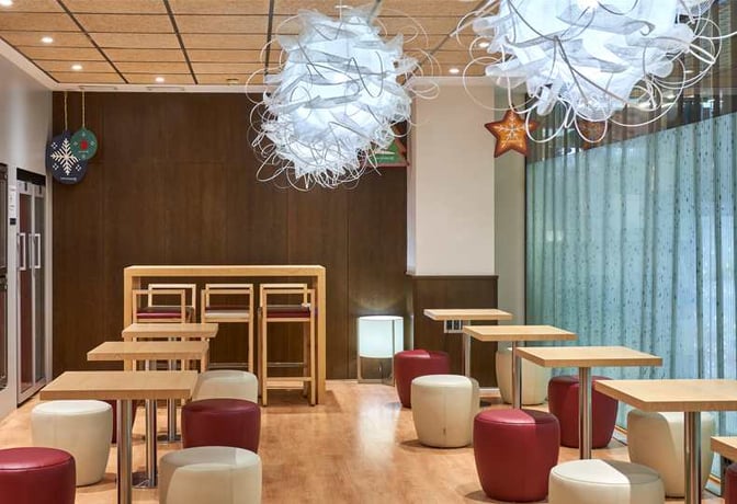 The Sala VIP Azahar at Seville Airport features a seating area with tables, stools, and decorative overhead lighting.