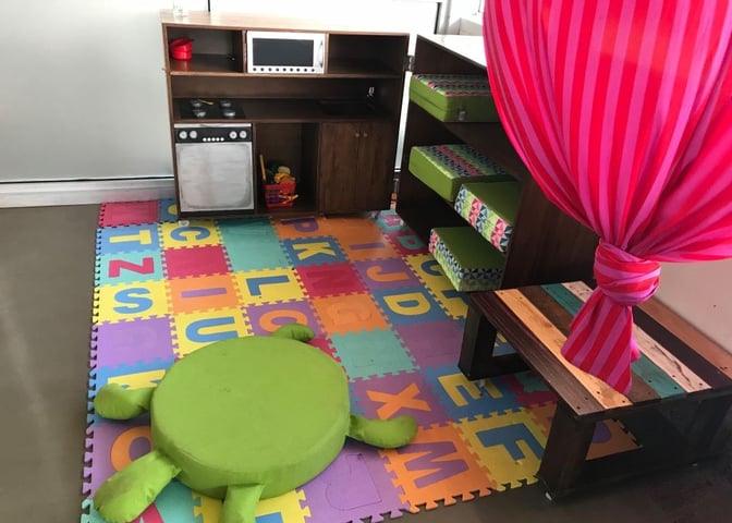 The children's play area at Aeropuertos VIP Club features a play kitchen, colorful foam mat, and cushioned seating for kids.