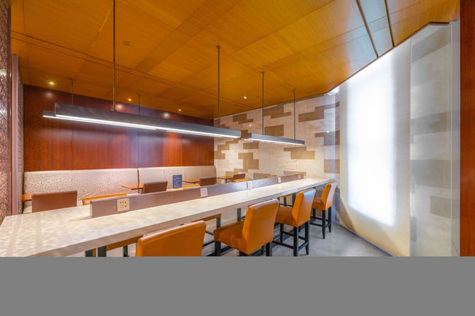 The seating area at Shanghai Hongqiao International Airport's lounge features a long counter with power outlets and cushioned chairs.