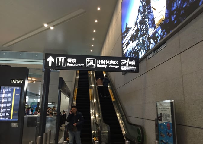 The image shows an escalator leading to the 21-Metre-Level VIP Lounge at Shanghai Hongqiao International Airport, with directional signage above.
