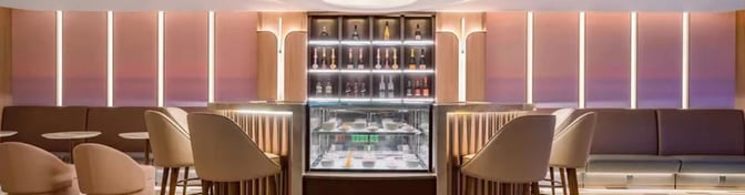 The Juneyao Airlines V6 VIP Lounge at Shanghai Hongqiao International Airport features a bar with seating and a display of beverages.