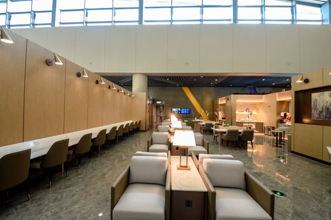 The China Eastern V01 International Lounge at Shanghai Hongqiao Airport features seating areas with workstations and a dining section.