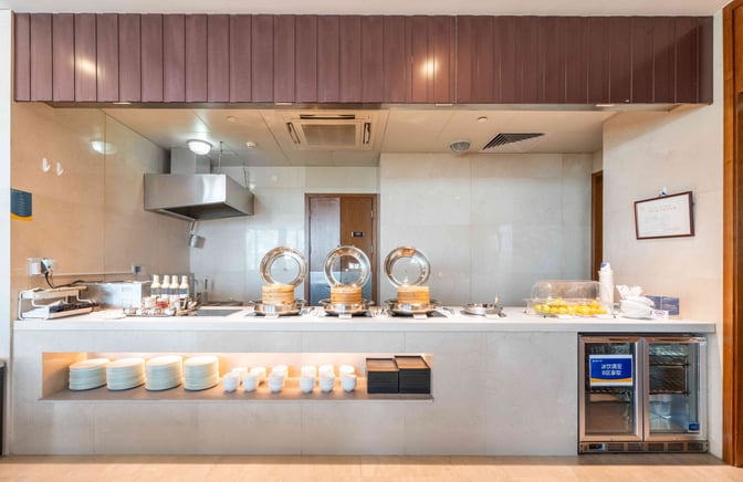 The V03 VIP Lounge at Shanghai Hongqiao International Airport features a self-serve food station with hot dishes and tableware.