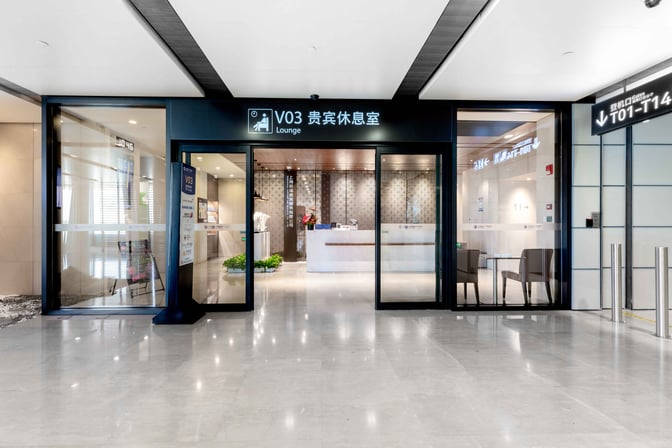 The entrance to the V03 VIP Lounge at Shanghai Hongqiao International Airport features sliding glass doors and a reception area inside.