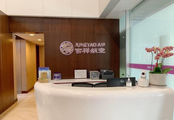 The Juneyao Air VIP Lounge entrance at Shanghai Pudong International Airport features a reception desk with informational materials and a potted plant.