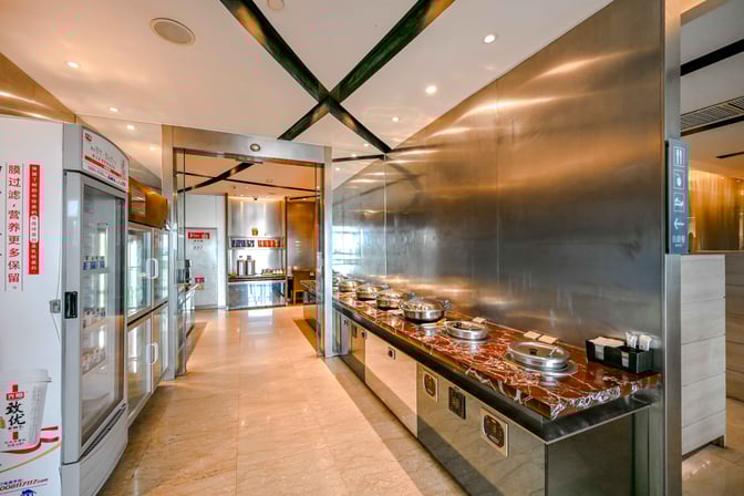 The First Class Lounge at Shanghai Pudong International Airport features a buffet area with hot food stations and refrigerated beverage displays.