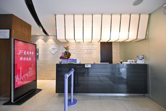 The reception area of the First Class Lounge at Shanghai Pudong International Airport features a check-in counter and digital display.