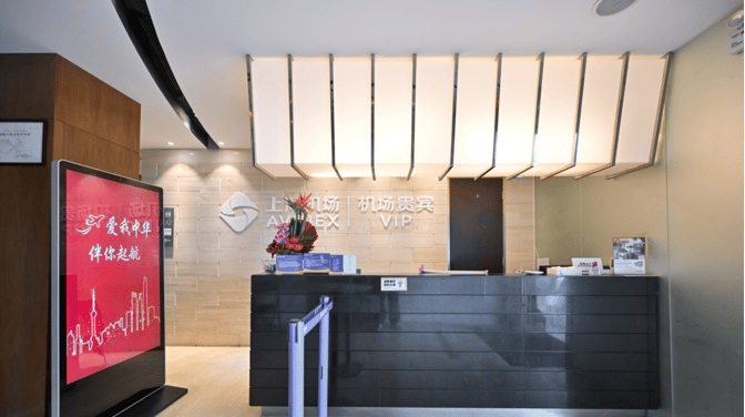 The reception area of the First Class Lounge at Shanghai Pudong International Airport features a check-in counter and digital signage.