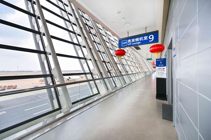 The entrance to VIP Lounge No.9 at Shanghai Pudong International Airport is located along a corridor with large windows overlooking the tarmac.