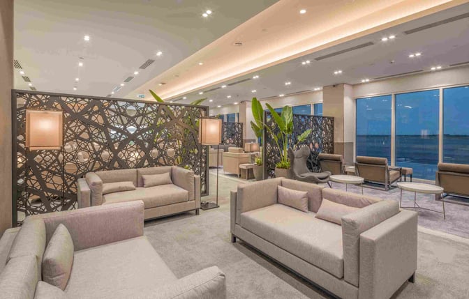 The seating area at Sharjah International Airport's lounge features comfortable sofas, decorative partitions, and views of the airport runway.