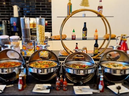 Buffet area at Pearl Lounge, Sharm el-Sheikh Airport, offers a variety of hot dishes with condiments and self-serve breakfast options.