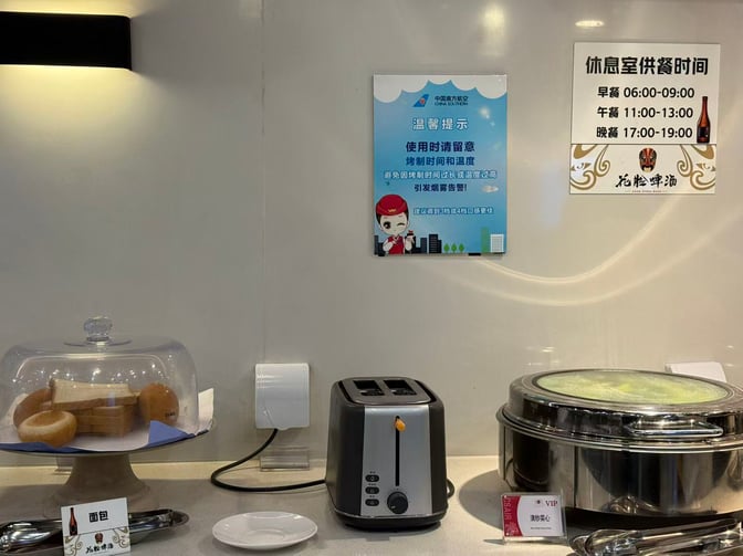The self-serve breakfast station at China Southern Lounge, Shenyang Airport, features bread, a toaster, and a covered hot dish.
