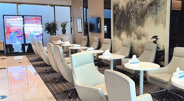 The seating area in the China Southern Lounge at Shenyang Taoxian International Airport features comfortable chairs and small round tables.