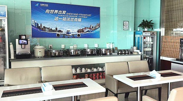 The lounge at Shenyang Taoxian International Airport features a self-serve food station with hot dishes and seating for dining.