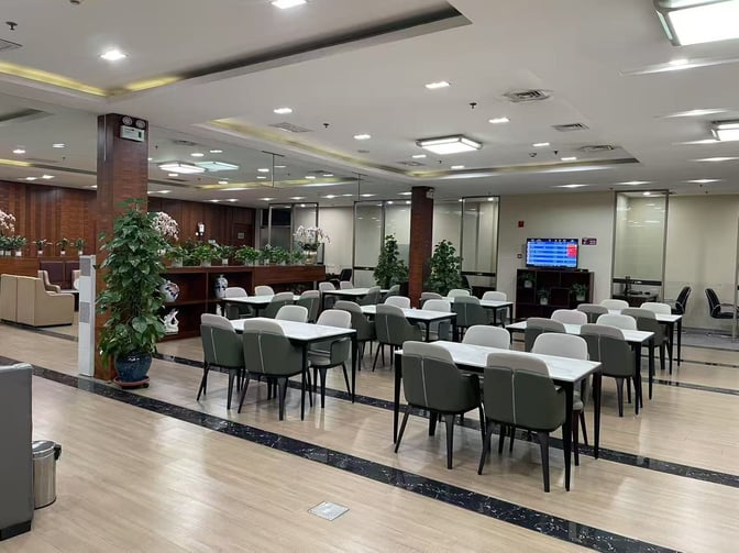 The seating area in the Easy Boarding Lounge at Shenyang Taoxian International Airport features tables and chairs with a flight information screen.