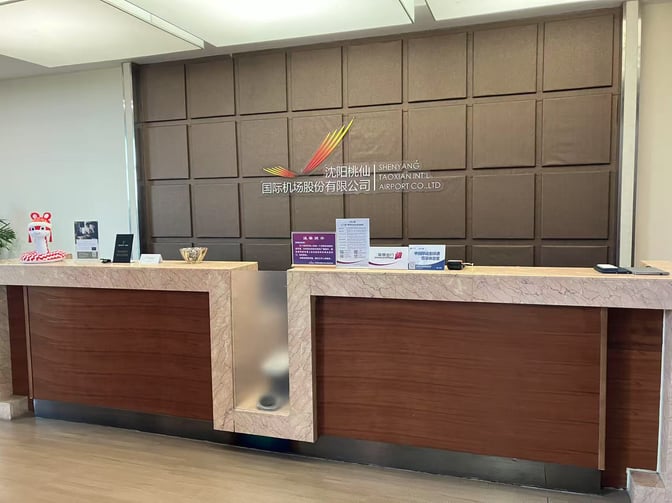 The reception desk at Shenyang Taoxian International Airport's Easy Boarding Lounge provides check-in services with informational displays and promotional materials.