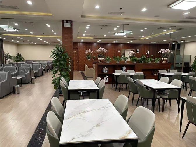 The Easy Boarding Lounge at Shenyang Taoxian International Airport features dining tables and comfortable seating with decorative plants.