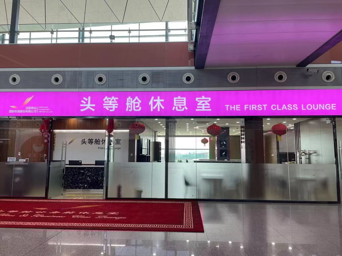The entrance to the International First Class Lounge at Shenyang Taoxian International Airport features a reception desk and glass doors.