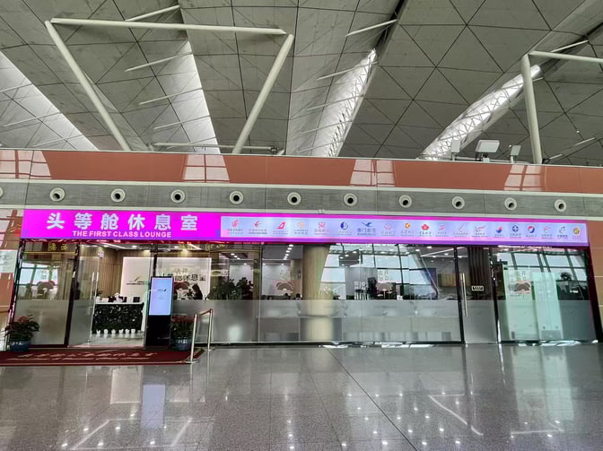The First Class Lounge entrance at Shenyang Taoxian International Airport features a reception area and visible seating through glass walls.