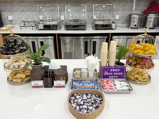 The self-serve snack station in Shenyang Taoxian International Airport's First Class Lounge offers packaged snacks, tea, and coffee options.