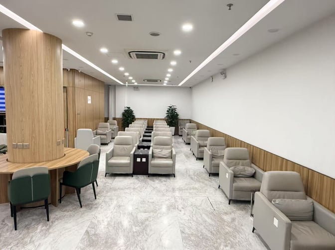 The seating area in Shenyang Taoxian International Airport's First Class Lounge features rows of cushioned chairs and a round table with chairs.