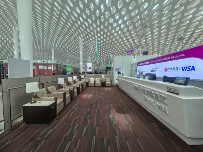 The C24 Business VIP Lounge at Shenzhen Bao'an International Airport features a reception desk and comfortable seating with individual lamps.
