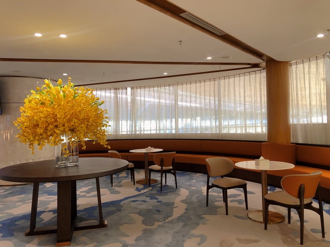 The seating area in Domestic VIP Lounge 3 at Shenzhen Bao'an International Airport features round tables, chairs, and a decorative floral arrangement.