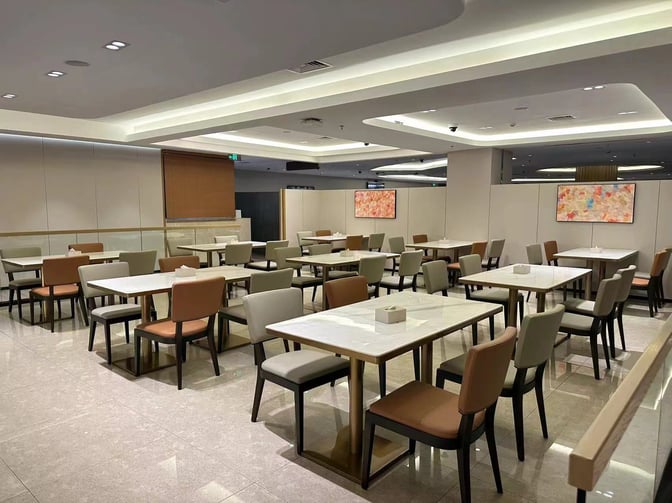 The Shenzhen Airport Domestic VIP Lounge 2 features a spacious seating area with multiple tables and chairs for dining and relaxation.