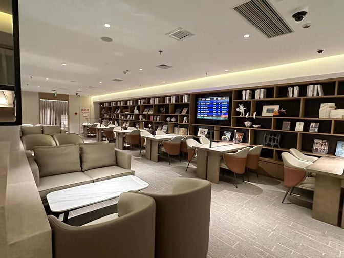 The Shenzhen Airport Domestic VIP Lounge 2 features seating areas with tables, bookshelves, and a flight information display screen.