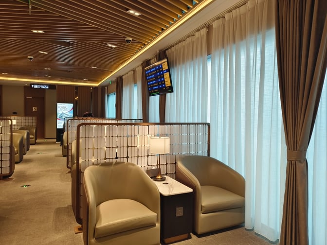 Seating in Shenzhen Airport Domestic VIP Lounge 2 features individual chairs with privacy screens and a view of flight information displays.