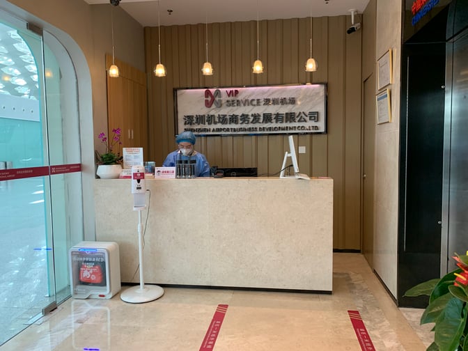 The reception area of Shenzhen Airport Domestic VIP Lounge 2 features a staffed desk and signage, located near the entrance.