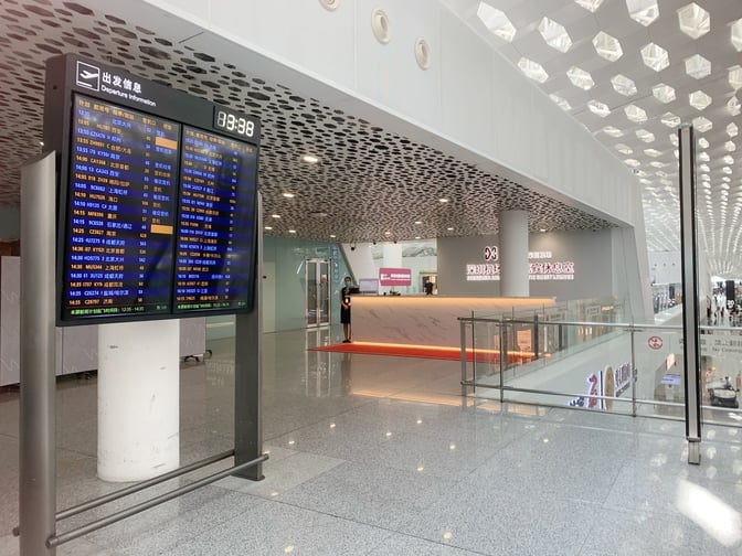 The Domestic Guest Lounge entrance at Shenzhen Bao'an International Airport is located near a departure information board displaying flight details.
