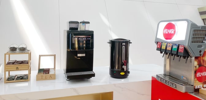 The beverage station in Shenzhen Bao'an International Airport's domestic guest lounge offers a coffee machine, hot water dispenser, and soda fountain.