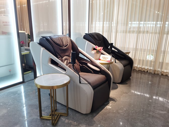 The China Southern Guest Lounge at Shenzhen Bao'an International Airport features massage chairs with adjacent small tables for passenger relaxation.