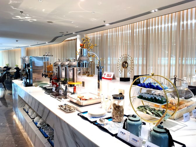The China Southern Guest Lounge at Shenzhen Bao'an International Airport features a self-serve food station with beverages, snacks, and breakfast items.