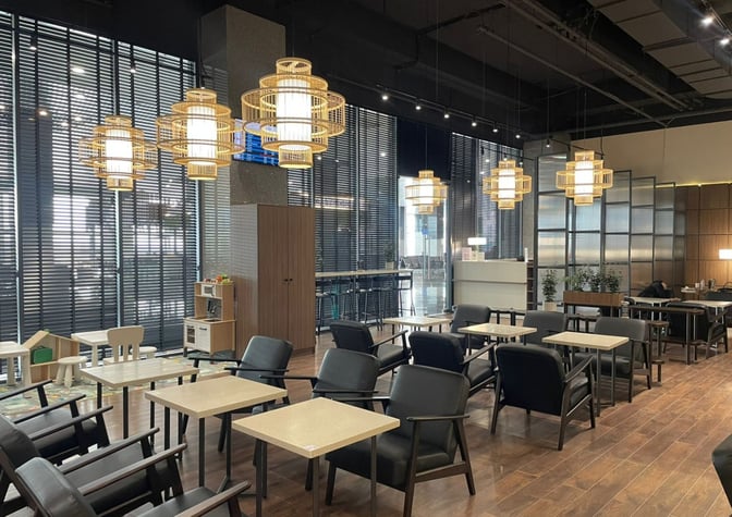 The Sky Hall Lounge at Shymkent International Airport features a seating area with tables, chairs, and a children's play section.