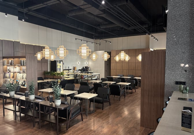The Sky Hall Lounge at Shymkent International Airport features a seating area with tables and chairs, adjacent to a self-serve food station.