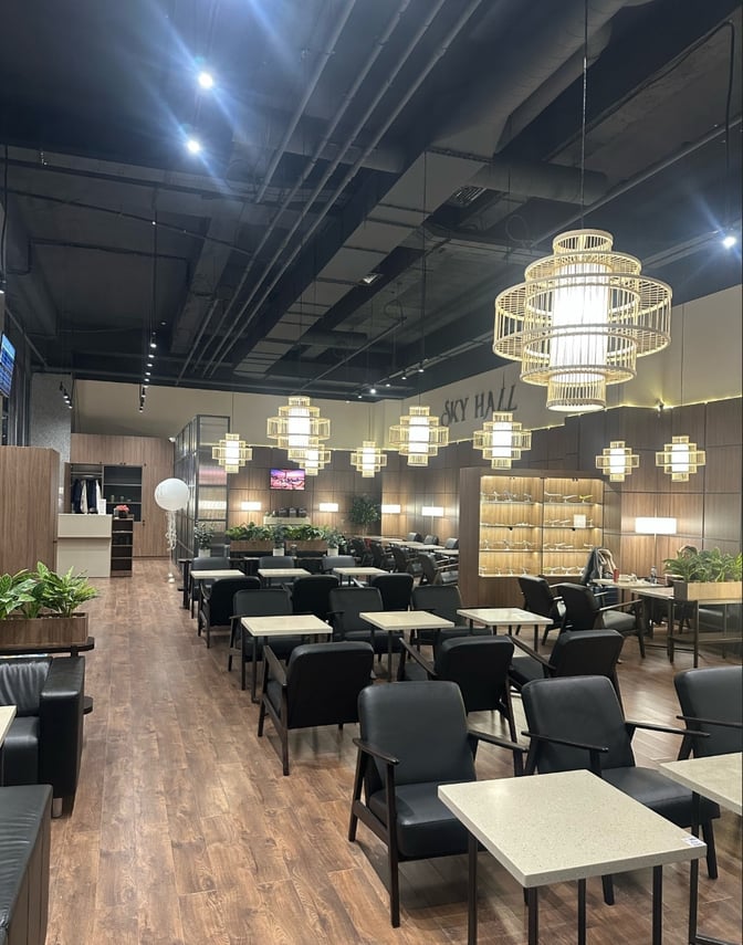 The Sky Hall Lounge at Shymkent International Airport features a spacious seating area with tables and chairs for travelers.
