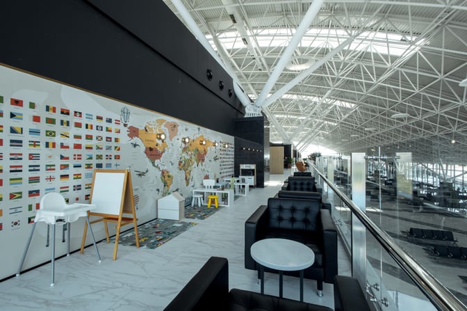 The Sky Hall Lounge at Shymkent International Airport features a seating area with sofas and tables, adjacent to a children's play area.