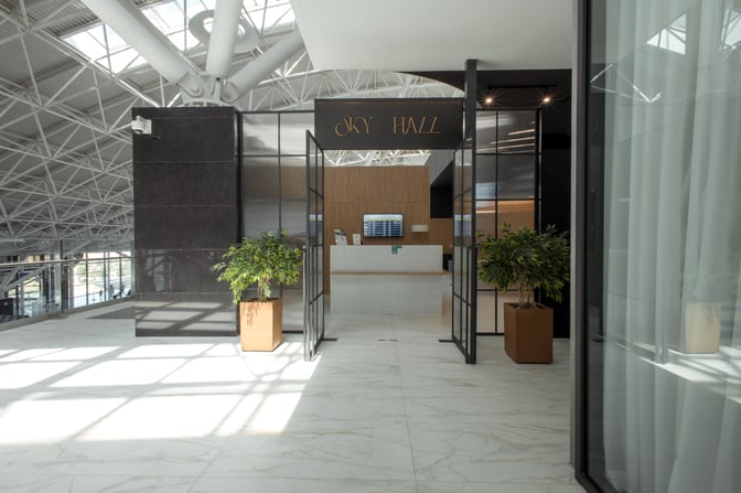The entrance to Sky Hall Lounge at Shymkent International Airport features a reception desk and flight information display.