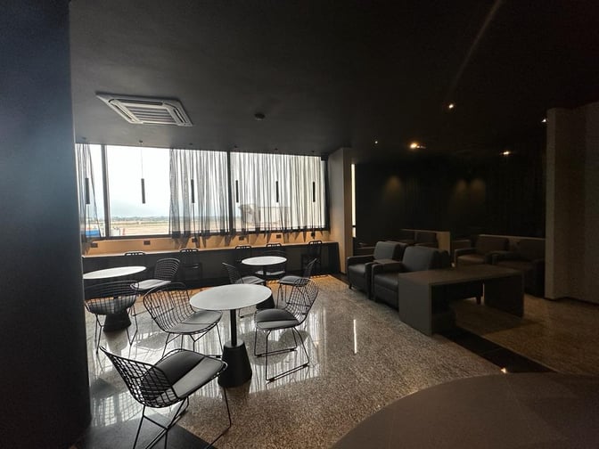 The Sala VIP Black at Silvio Pettirossi International Airport features seating with tables and chairs, offering views of the tarmac.