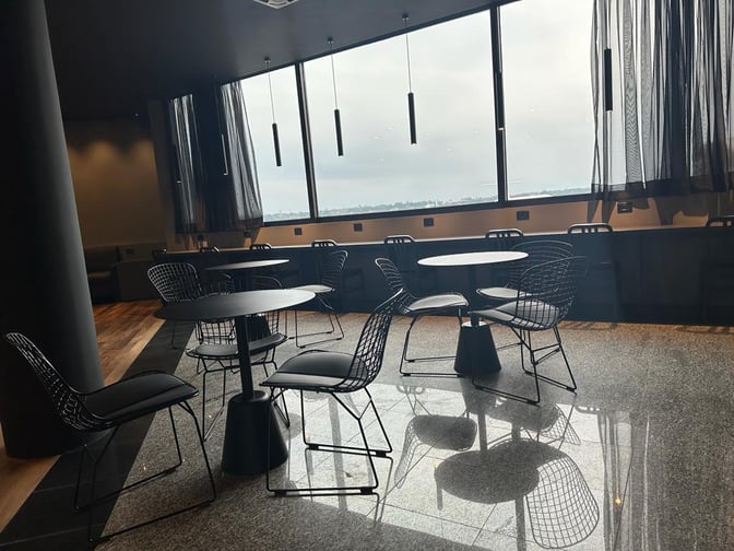 The seating area in Sala VIP Black at Silvio Pettirossi International Airport features round tables and chairs with large windows.