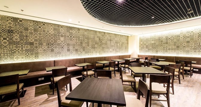 The seating area in Marhaba Lounge at Singapore Changi Airport features tables and chairs with patterned wall decor for dining.