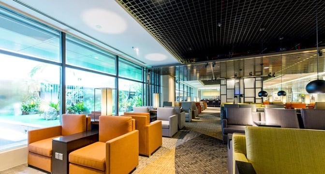 The Marhaba Lounge at Singapore Changi Airport features spacious seating areas with armchairs and tables, adjacent to large windows.