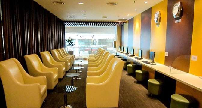 The SATS Premier Lounge at Singapore Changi Airport features a seating area with armchairs and a computer station for passenger use.